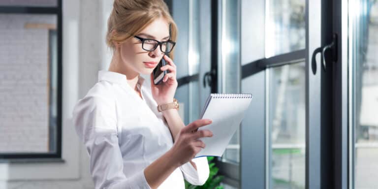 Office worker taking a call with notpad of tips