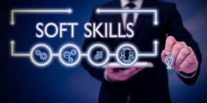 A man in a suit is holding up a sign that says soft skills.