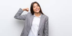 A young business woman flexing her arm.