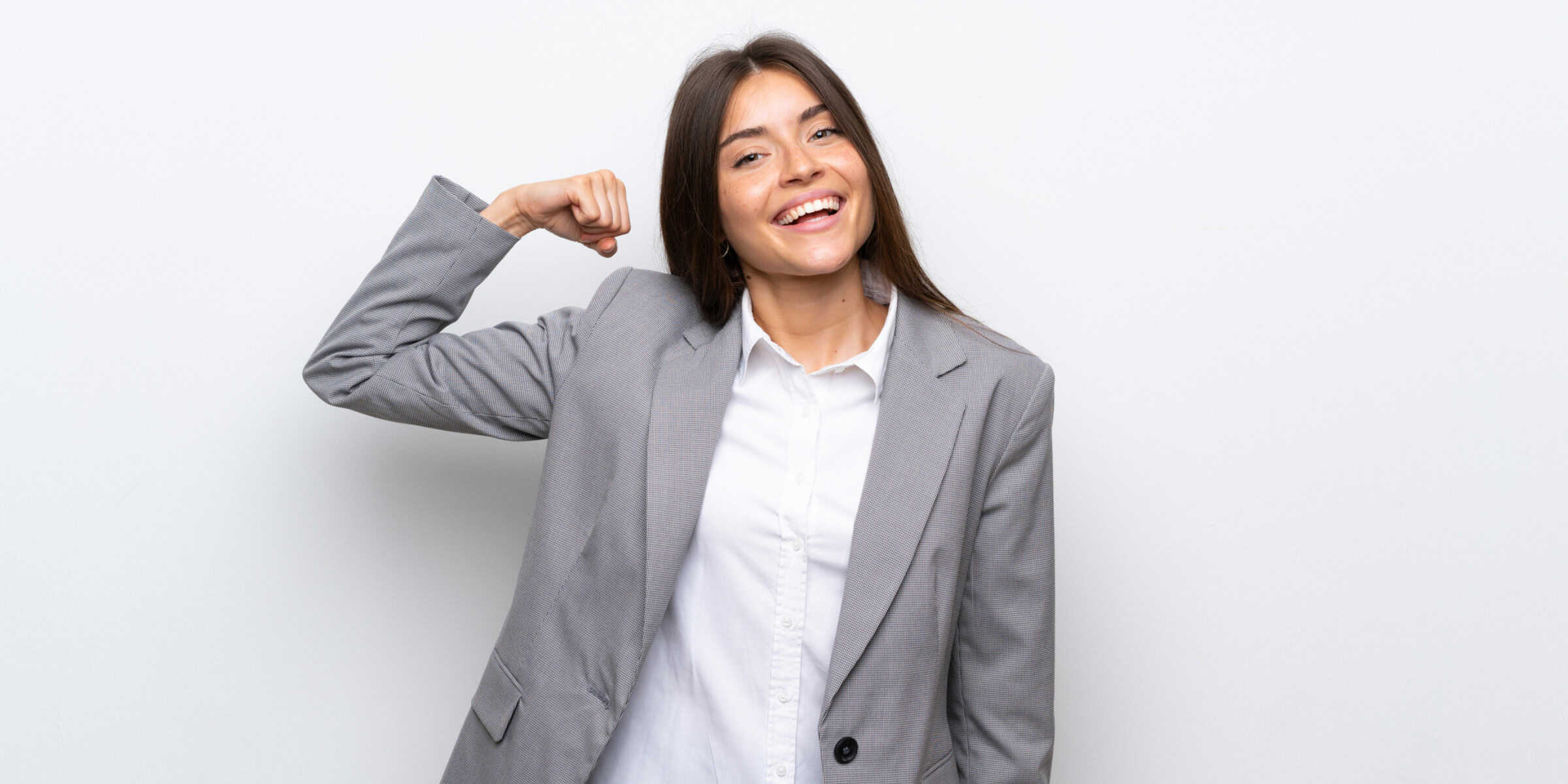 A young business woman flexing her arm.