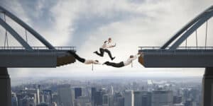 A group of business people jumping over a bridge.