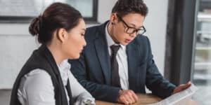 Two business people sitting at a table looking at a document.