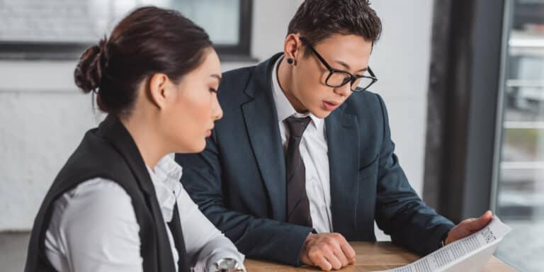 Two business people sitting at a table looking at a document.