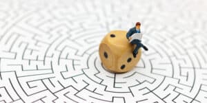 A businessman sitting on a dice in a maze.
