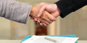 Two people shaking hands over a document.