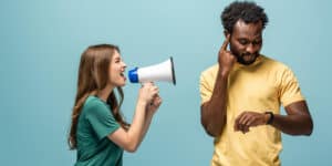 A man and a woman shouting into a megaphone on a blue background.