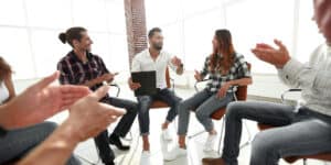 A group of people sitting around a table and clapping.