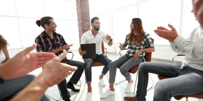 A group of people sitting around a table and clapping.