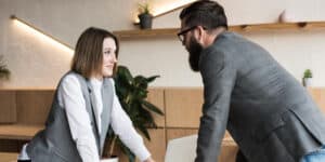 A man and a woman talking at a desk in an office.