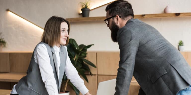 A man and a woman talking at a desk in an office.
