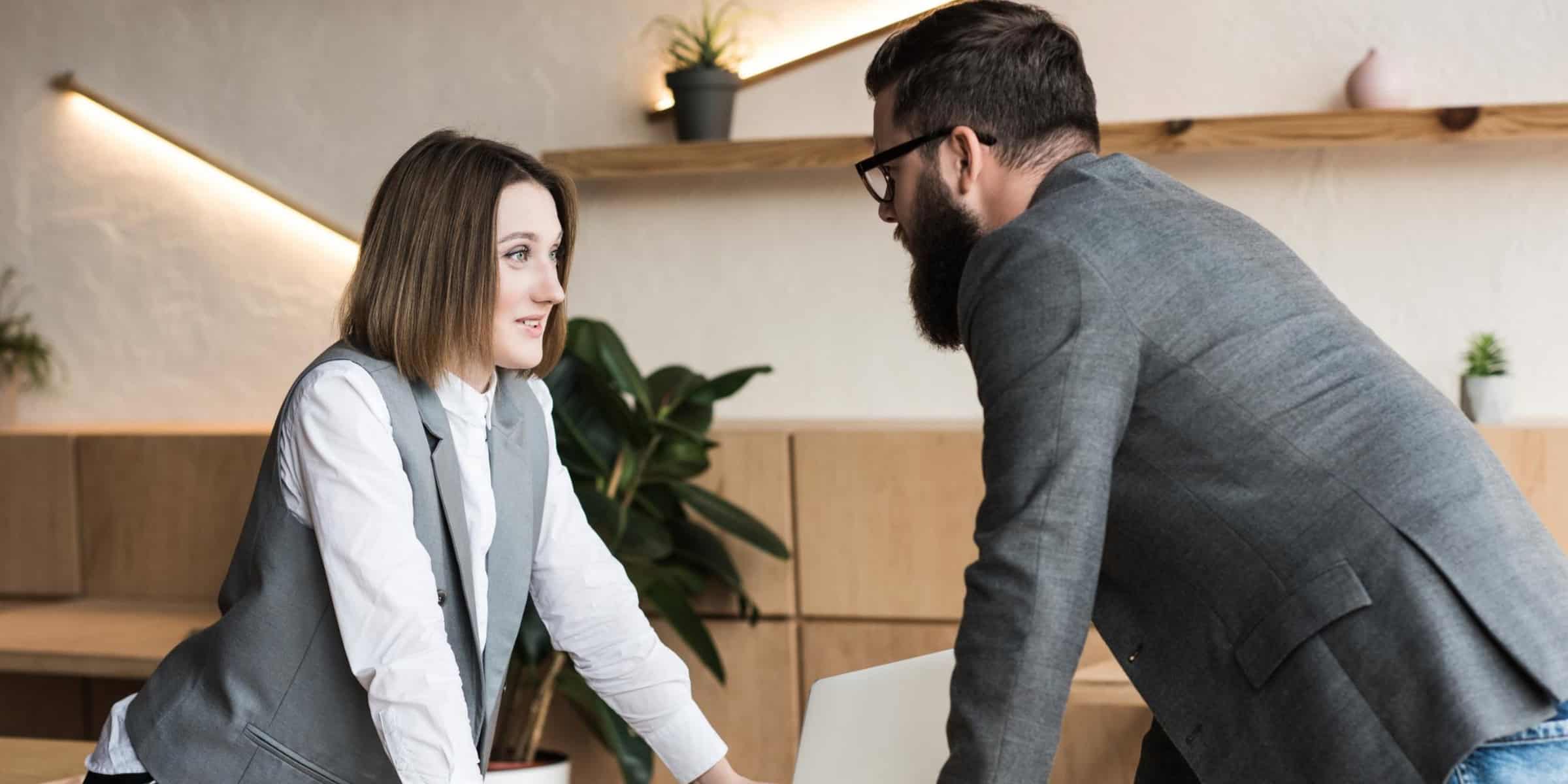A man and a woman talking at a desk in an office.