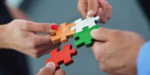 A group of people holding a puzzle piece together.
