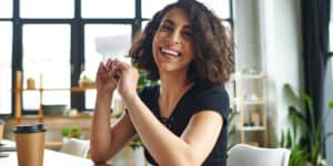 A smiling woman sitting at a desk with a cup of coffee.