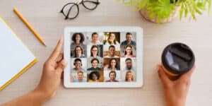 A person holding a tablet with a group of people on it.
