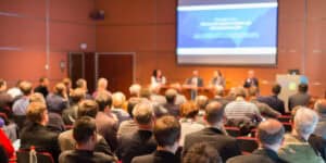 A large group of people sitting in a conference room.