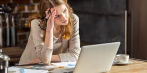 A woman is sitting at a table with a laptop in front of her.