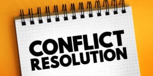 A notepad with the word conflict resolution on it.