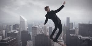 Businessman balancing on a tightrope over a city.
