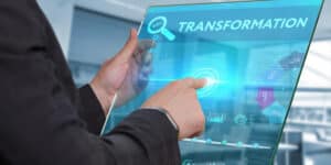 A man in a suit is pointing at a screen with the word transformation.
