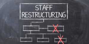 A blackboard with the word staff restructuring written on it.