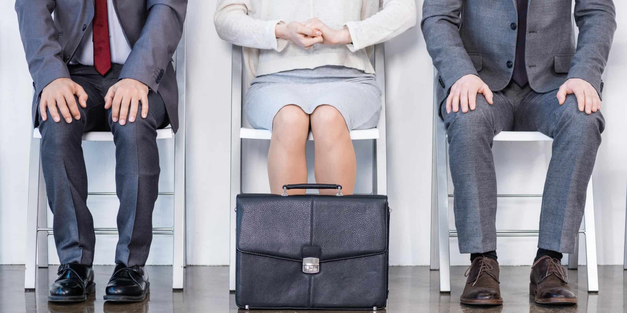 A group of business people sitting on chairs in front of a white wall.