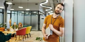 A man leaning against a wall in an office.