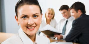 A woman is smiling in front of a group of people.