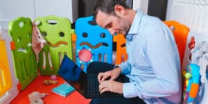 A man working on a laptop in a baby's room.