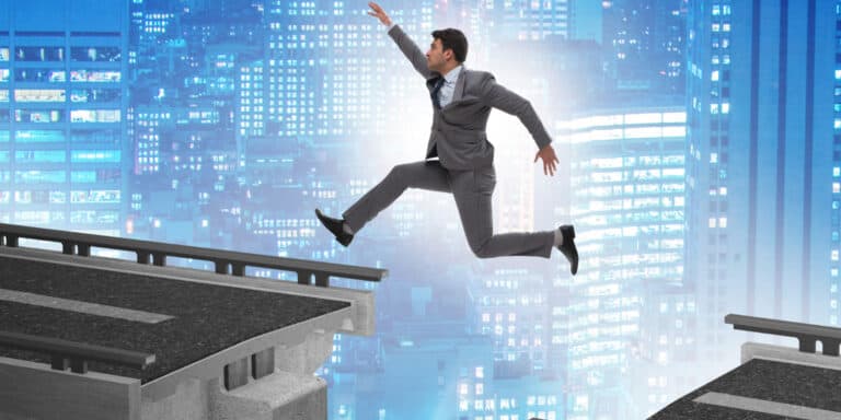 A businessman jumping over a bridge over a city.