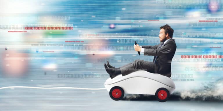 A man in a suit is driving a toy car.