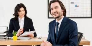 A man and woman sitting at a desk in an office.