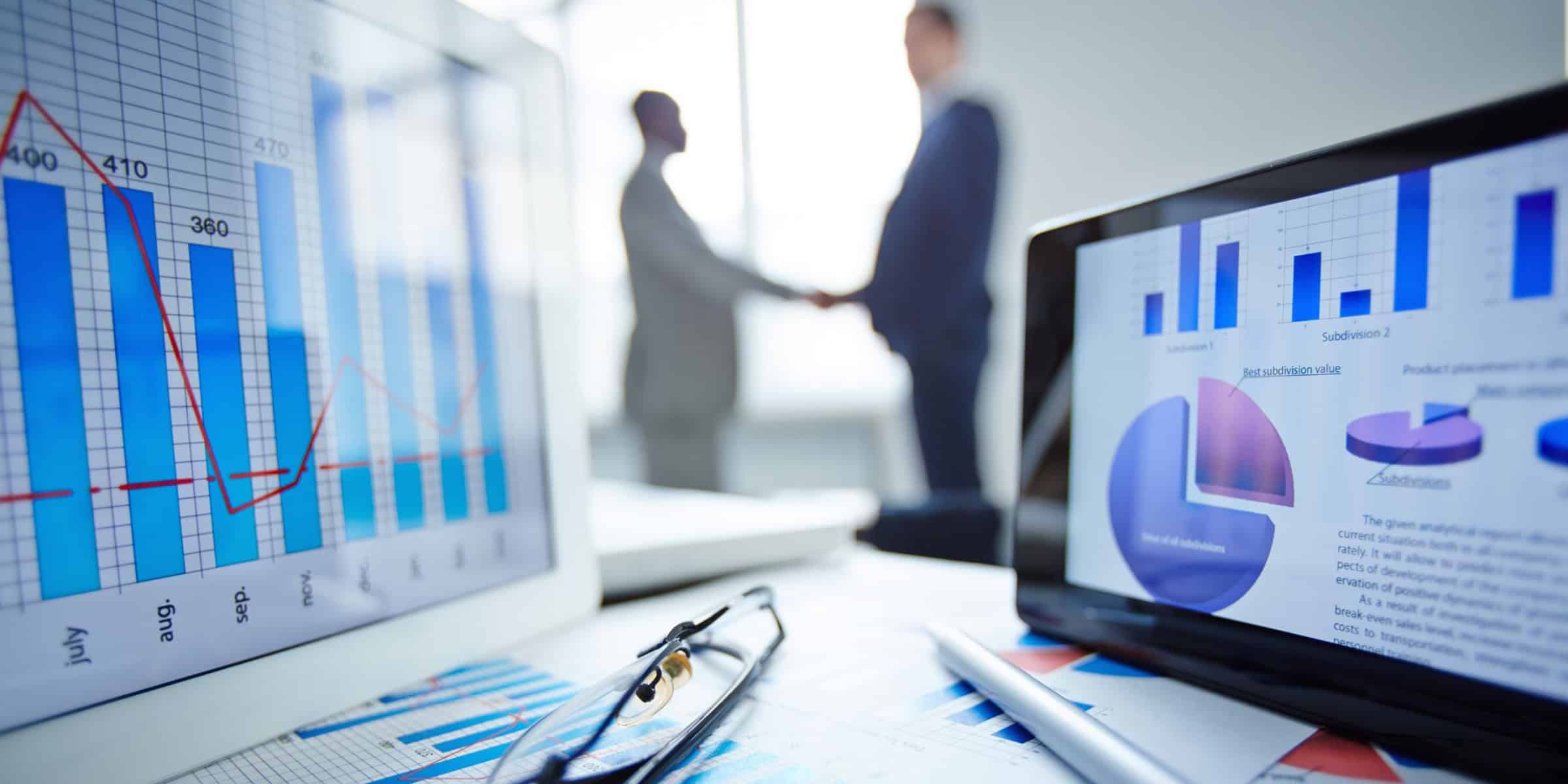 A laptop with graphs on it and a businessman shaking hands in a corporate setting.
