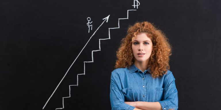 A young woman standing in front of a blackboard with stairs drawn on it.