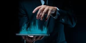 A businessman is holding a tablet with a city on it.