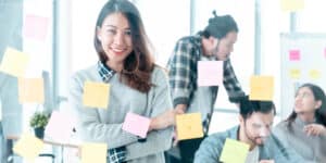 A group of people in an office with sticky notes on the wall.