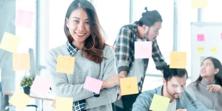 A group of people in an office with sticky notes on the wall.