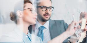 Two business people working together on a whiteboard.