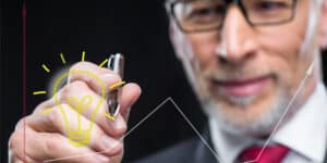 A businessman drawing a light bulb on a graph.