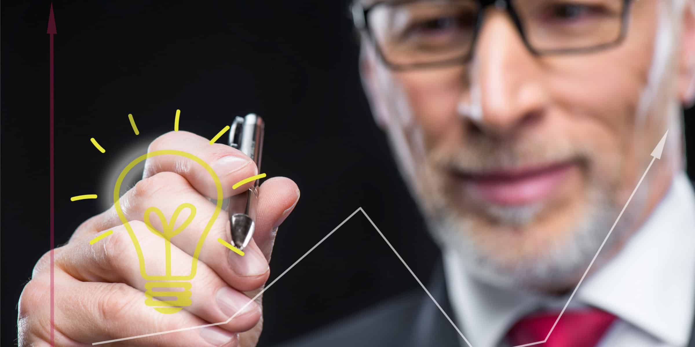 A businessman drawing a light bulb on a graph.