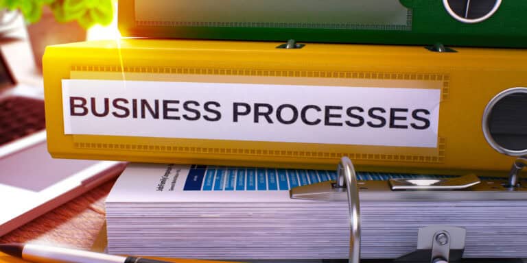 A stack of binders with the word business processes on them.