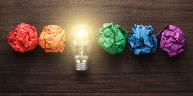 A light bulb surrounded by colorful crumpled paper.