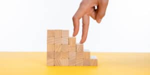 A woman's hand reaching up to a stack of wooden blocks.