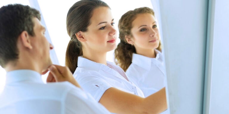 A group of business people looking at a mirror.