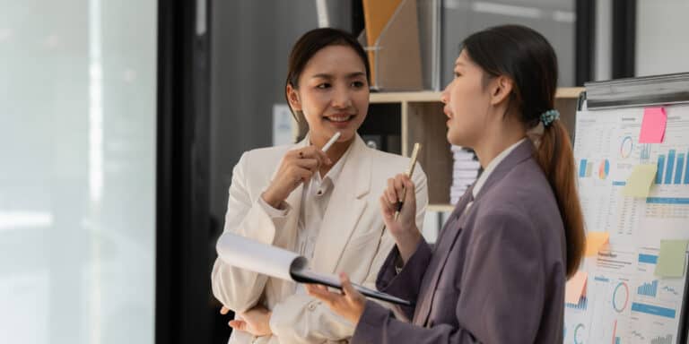 Two business women talking in an office.