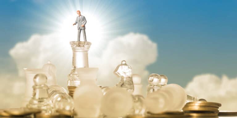 Businessman standing on top of chess pieces.