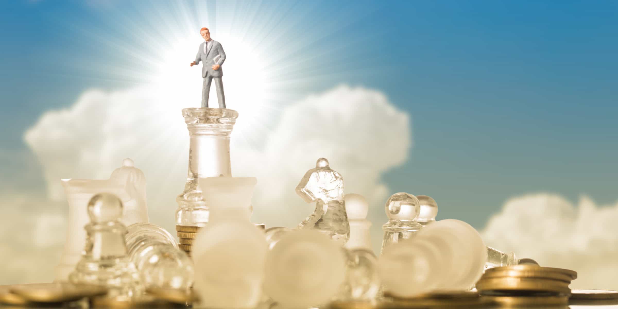 Businessman standing on top of chess pieces.