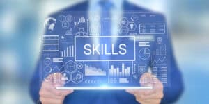 A businessman holding a tablet with the word skills on it.