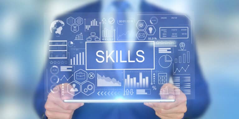 A businessman holding a tablet with the word skills on it.
