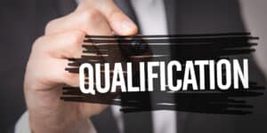 A man in a suit holding a sign with the word qualification.