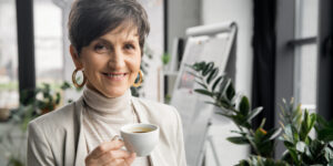 A woman holding a cup of coffee in an office.